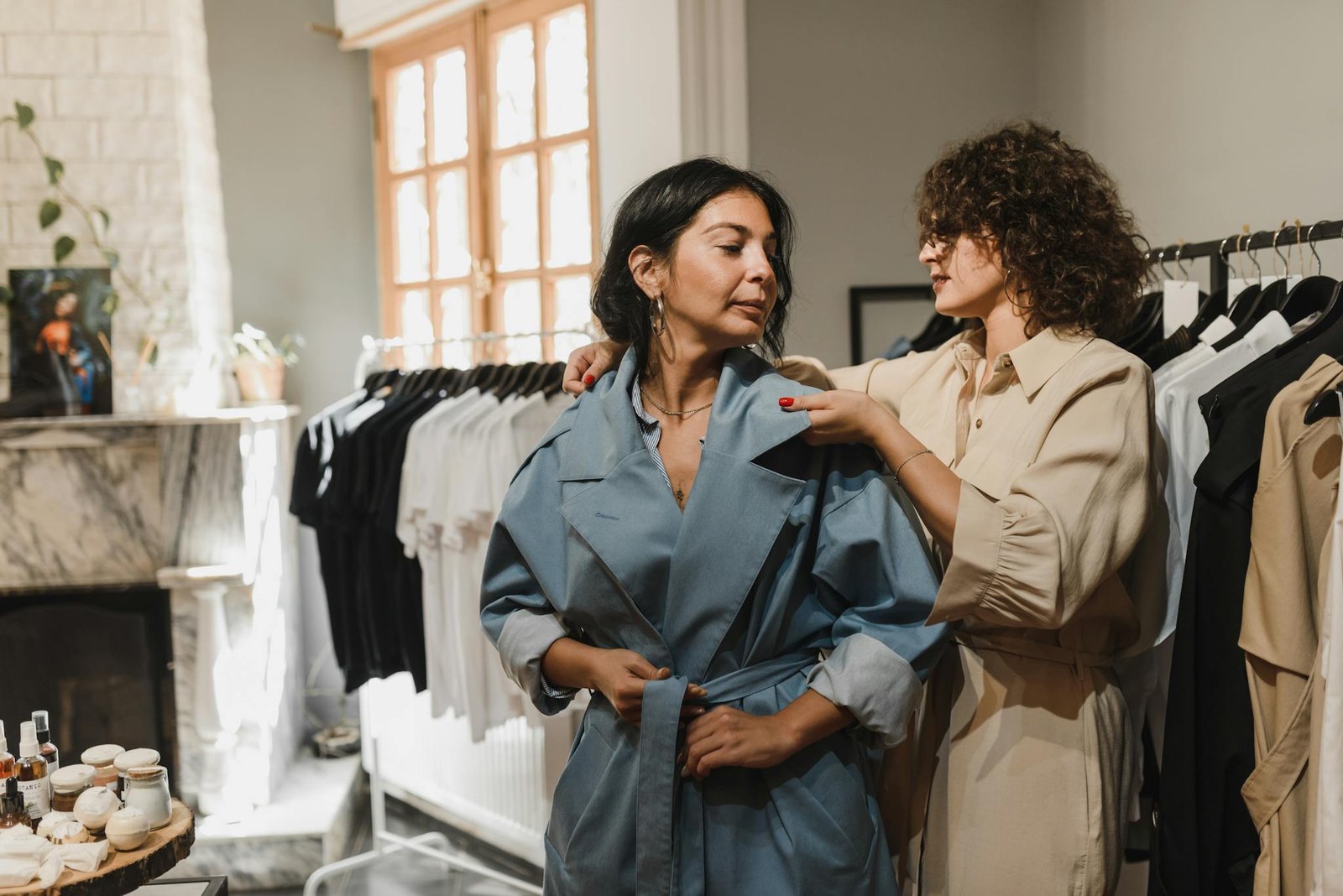 Two women explore fashion choices indoors, surrounded by stylish clothing racks.